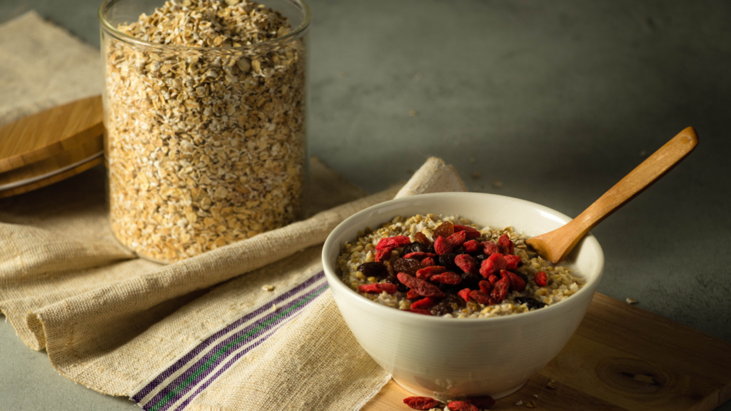 Healthy oatmeal bowl with goji berries and raisins beside a jar of dry oats, showcasing products from a trusted instant oats manufacturer.