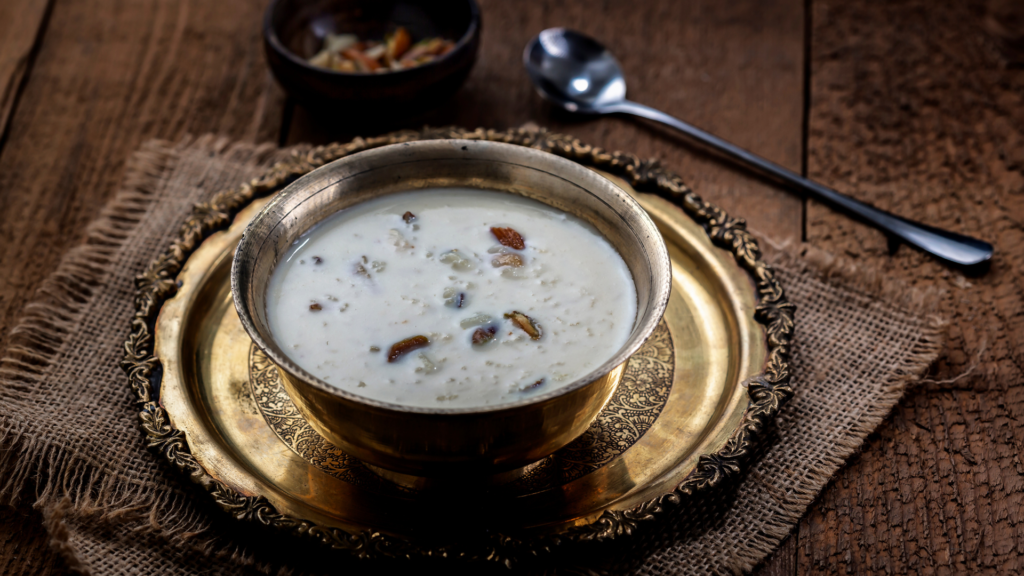 Traditional Palada Payasam served in a brass bowl on an ornate golden plate, garnished with dry fruits, placed on a rustic wooden background.