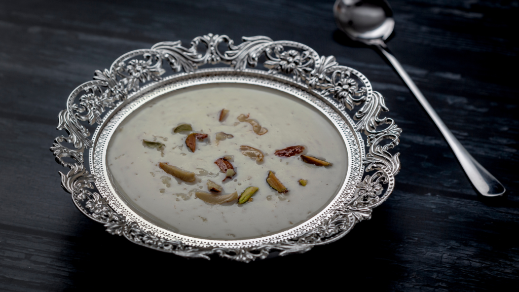 Traditional Palada Payasam served in an ornate silver bowl, garnished with roasted dry fruits, placed on a dark wooden surface.