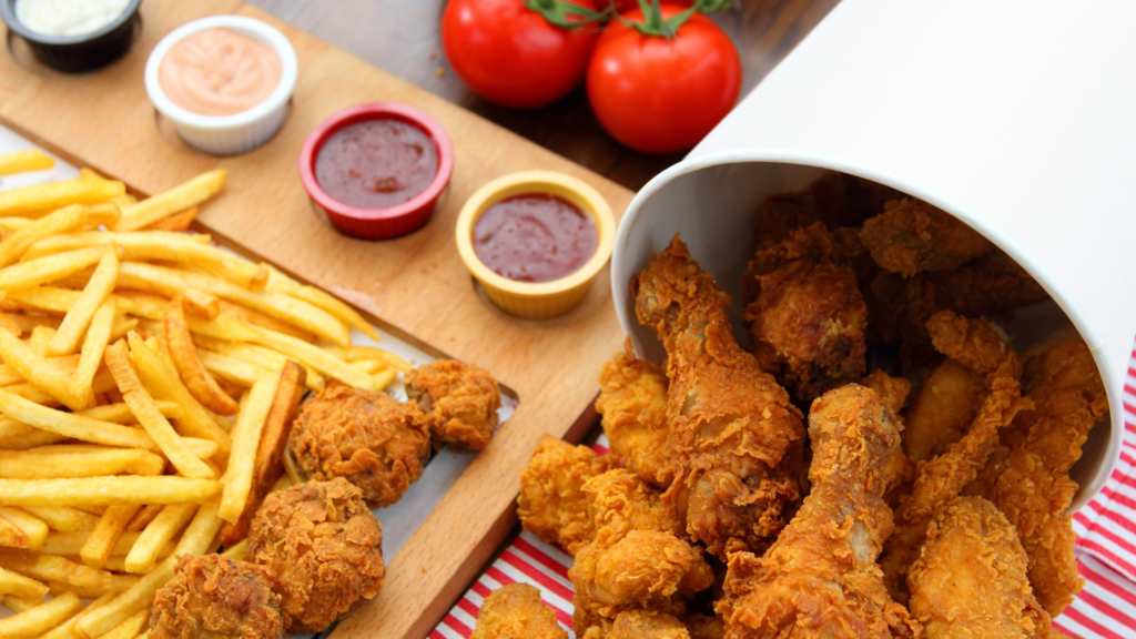 A bucket of crispy fried chicken served with golden fries and dipping sauces.